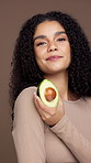 Avocado, happy and face of woman in studio for skincare, natural cosmetics and facial care. Brown background, dermatology and portrait of person with fruit for vitamin E, organic benefits and beauty