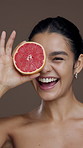 Grapefruit, happy and face of woman for skincare, facial treatment and anti aging on studio background. Dermatology, beauty and portrait of person with fruit for vitamin c, natural glow and hydration