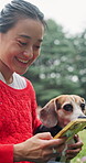 Dog, phone and smile of woman outdoor to search for pet insurance options or quotes online. App, bonding or social media with beagle puppy and owner in nature for animal protection plan subscription