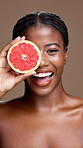 Skincare, grapefruit and face of black woman in studio with natural, organic or cosmetic routine. Portrait, dermatology and African person with citrus fruit for facial brightening by brown background