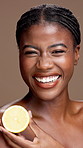 Black woman, face or skincare with lemon for diet, detox or vitamin C on a brown studio background. Portrait, female person or happy model with smile or natural organic fruit for citrus acid or fiber