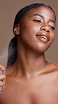 Black woman, face and spray perfume for beauty, grooming and luxury scent in studio. Cosmetics, fragrance and happy model with bottle for self care, clean smell and hygiene on brown background