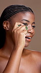Gua sha, face and skincare with black woman in studio for natural skin treatment or wellness. Beauty massage, jade stone and smile of model person on brown background for cosmetic dermatology routine