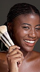 Brush, beauty and face of black woman in studio with makeup, confidence and facial routine. Glow, foundation and portrait of African person with cosmetic tool for cosmetology by gray background.