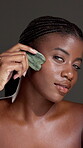 Skincare, gua sha and face of black woman in studio for lymphatic drainage, self care or detox. Jade facial tools, holistic treatment and natural beauty with person on dark background for circulation
