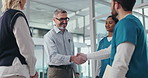 Man, doctors and handshake with group at hospital with welcome, onboarding and happy in corridor. People, medical director and shaking hands with smile, recruitment or hiring with team at clinic