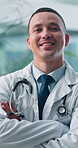 Face, confident doctor and happy man in hospital for healthcare service, wellness or about us. Portrait, medical professional and smile with arms crossed as general practitioner or employee in Spain