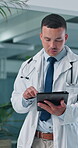 Doctor, man and tablet with typing at hospital, review or telehealth consulting, notification or chat. Person, medical professional and tech with application, scroll or feedback for report at clinic