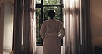 Woman, reflection and thinking by window in bedroom with pajamas, inspiration and wake up in home. Person, back and perspective with insight, memory or decision in morning with nightgown at apartment