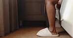 Slippers, morning and legs of person in bedroom for wake up, getting ready and hotel lodge. Comfortable, hospitality and calm, with closeup of feet and shoes in resort for relax, peace and break