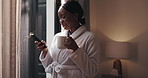 Black woman, phone and coffee in bedroom, window and smile with texting, contact and notification in home. African person, smartphone and happy with tea cup, web chat and social network at house