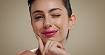 Beauty, smile and wink with face of woman on studio background for dermatology results or satisfaction. Cosmetics, skincare and touching with happy model on space for facial treatment or wellness