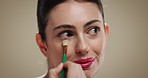 Woman, makeup brush and eyeshadow for powder, beauty and application on studio background. Creative, person and model with tools, process and aesthetic for cosmetics for wellness and transformation
