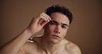 Face, man and tweezer with eyebrows for skincare, hair removal and grooming in studio background. Portrait, male person and tools for beauty, facial maintenance and trimming process of transformation