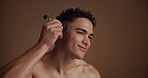 Face roller, skincare and man in studio, beauty and dermatology on brown background. Space, jade crystal and person with rose quartz, wellness and anti aging with cosmetics, aesthetic and grooming
