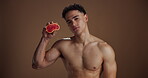 Face, man and grapefruit for skincare in studio for vitamin c, brighten skin and natural detox. Portrait, male person and fruit with beauty, organic benefits and dermatology glow on brown background
