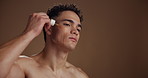 Man, oil dropper and skincare in studio, low angle or product with mockup space on background. Person, pipette and application with serum, dermatology or moisturiser with hyaluronic acid for benefits