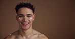 Face, cream and man in studio, dermatology and wellness with beauty on brown background. Portrait, space or person with lotion, healthy skin or cosmetics with aesthetic, shine or treatment with creme