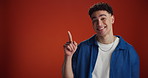 Mockup, pointing and face of man in studio for announcement, notification and discount news. Space, happy and portrait of person with gesture for information, promotion and choice on red background