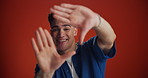 Face, frame and palm with man on red background for film, photography or production. Hands, picture and smile of happy model isolated in studio to measure, shape or size shot for videography