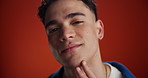 Happy man, face and flirt with wink in studio for clean skin, shave or beauty on a red background. Portrait, handsome or male person with confident smile or emoji for romance, secret or body language
