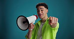 Megaphone, pointing and face of man in studio for announcement, notification and news. Space, mockup and portrait of person with bullhorn for information, encouragement and choice on blue background
