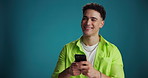Phone, smile and thinking with man on blue background for communication, social media or text message. App, idea and typing with happy person on space in studio for choice, decision or planning