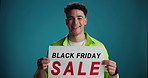 Poster, sale and face of man excited in studio for discount, bargain and deal news on blue background. Happy, space and portrait of person with banner for announcement, promotion or black Friday info