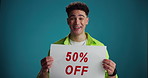 Poster, sale and face of man in studio excited for discount, bargain and deal news on blue background. Happy, space and portrait of person with banner for announcement, promotion and information