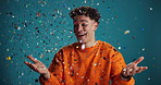 Surprise, wow and face of man with confetti in studio for lottery prize, competition winner or deal. Blue background, person or excited with giveaway for game show promotion, achievement or milestone