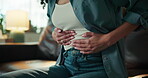 Stomach ache, crisis and period pain with woman on sofa for endometriosis, menstruation and cramps. Abdomen, ovarian fibrosis and emergency with person in living room of home for inflammation