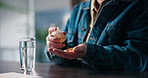 Pills, water and hands of man in home with medicine, prescription and adhd medication to focus. Health, student and person with container for vitamins, supplements and drugs for medical symptoms