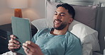 Tablet, happy and man in bed for online connection, social networking and internet in home. Relax, laughing and person on digital tech for streaming videos, browse website and notification in bedroom