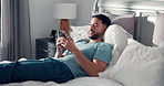 Happy man, relax and typing with phone in bed for social media, network service or message in home. Male person, thinking and lying with smile on mobile smartphone for online chatting, texting or app