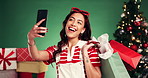 Happy woman, christmas and shopping bags with selfie in studio for picture on a green background. Female person, shopper or model with smile, presents or gifts for photography, festive memory or app
