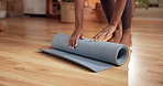 Person, hands and yoga mat with roll in home for workout completion, exercise or done activity. Active, feet or yogi folding equipment on wooden floor for stretch, zen or health and wellness in house