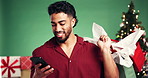 Man, phone and texting at Christmas in studio, shopping bag and typing for chat on background. Person, smartphone and happy with mobile app, click and social network with gift for xmas celebration