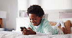 Morning, phone and relax with black child on bed in home for browsing, gaming or social media. App, mobile and smile of happy African boy in bedroom of apartment for communication or streaming