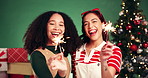 Christmas, sparkler and smile with friends in studio for celebration, support and holiday season. Happiness, festive event and xmas vacation with women on green background for December and dancing