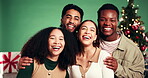 Friends, face and laugh in Christmas studio with people, holiday and festive cheer for bonding. Funny, portrait and group hug by tree for xmas celebration, presents or decoration on green background