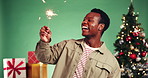 Man, sparkler and celebration with Christmas tree in studio, excited and laugh on background. African person, fireworks and happy with present, gift and party with festive holiday at xmas with boxes