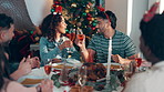 Christmas, social gathering and toast with friends in dining room of home together for celebration. Champagne, cheers and festive with group of people in apartment for bonding, holidays or tradition
