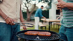 Cooking, bbq and food with hands of friends in backyard of home for party, social reunion and helping. Celebration, summer holiday and meat grill with people in garden of house for barbecue and lunch