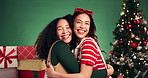 Friends, hug and face in Christmas studio with women, holiday and festive cheer for bonding. Laughing portrait and embrace by tree for xmas celebration, presents or decoration on green background