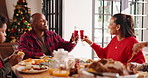 Family, meal and cheers for Christmas, home and beverage for celebration, bonding or festive season. Dinner, man and toast with woman, feast and happy on Xmas holiday, child and parents with drinks