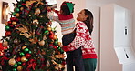 Mom, child and tree with decoration for Christmas, festive celebration or holiday tradition. Smile, woman and son with ornaments, help and flare for family bonding and prepare xmas season in home