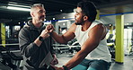Personal trainer, fist bump and man in gym on bike for cardio workout, exercise and fitness. Sports, sweat and coach with person for training, challenge and success for endurance, health and wellness