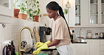 Home, washing dishes and black woman in kitchen, hygiene and tap with gloves, sink and disinfectant. Apartment, remove bacteria and African person with liquid, housekeeping and cleaning with faucet