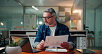 Business man, laptop and video call with documents for market insight, graph results and statistics. Analyst, night and mature person with virtual meeting in office for client feedback or performance