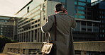 Back view, businessman and walking with phone call in city for conversation or discussion. Man, employee or talking with mobile smartphone or briefcase for travel or commute to work in an urban town